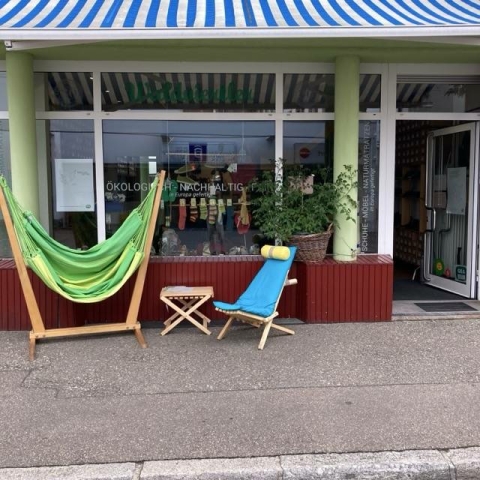 Außenansicht des GEA Freiburg Ladens in Freiburg mit Hängematte, Sitzgelegenheit und Blick auf das Schaufenster mit Schuhen.