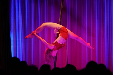 Artistin an der Stange im Spagat